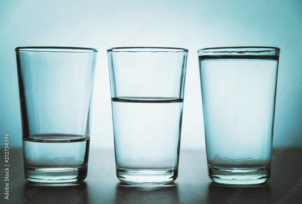 studio shot of three water glasses each one have more water than the other studio shot of three water glasses each one have more water than the other