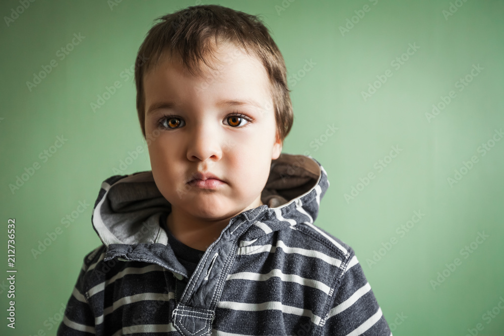 gloomy cute child boy standing holding hands in pullover pockets.Free space for advertisement gloomy cute child boy standing holding hands in pullover pockets.Free space for advertisement