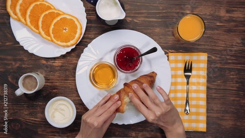 Close up on a young woman hands as she ieating fresh croissant with jam. photo