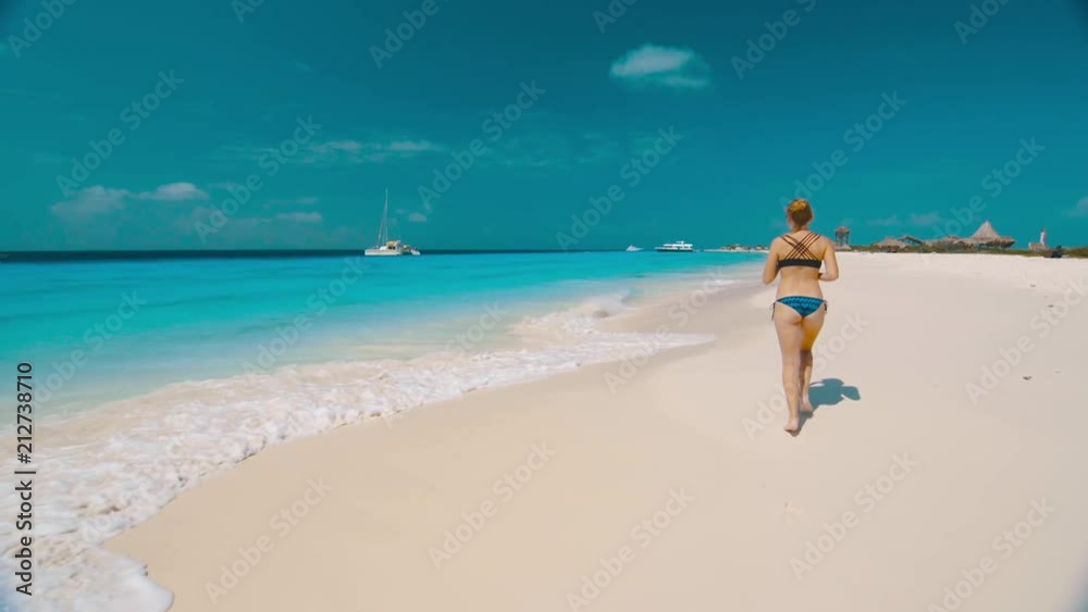 Girl in bikini running on beach, Klein Curacao Girl in bikini running on beach, Klein Curacao