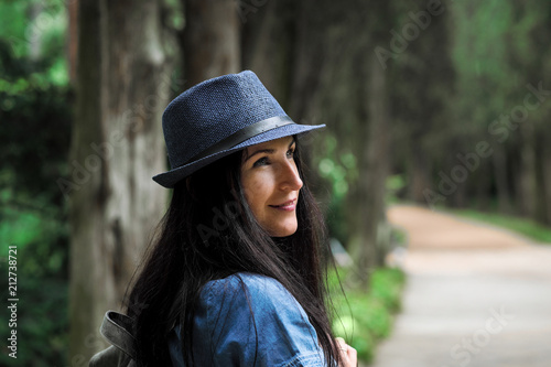 Portrait of a young beautiful woman in a blue dress and hat in the park.