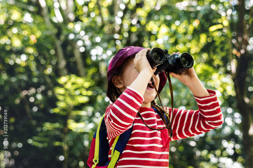 Little girl using binoculars in the forest
