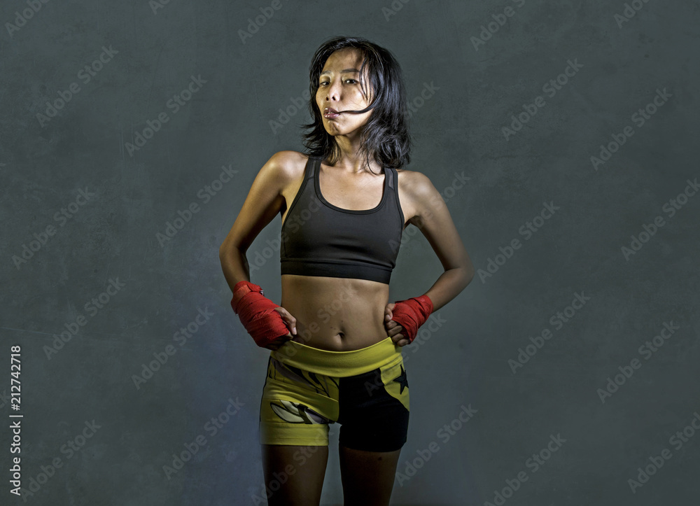 Obraz premium portrait of sporty and fit fighter Asian Chinese woman using wrist wraps training mma fight sport or boxing workout looking dangerous in badass pose