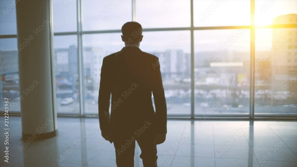 The man walking in the office hall on the sunset background. slow motion The man walking in the office hall on the sunset background. slow motion