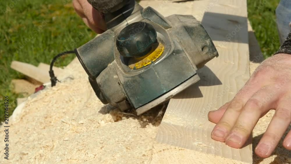 man working on a wood planing machine. Chips fly in different side from the planer man working on a wood planing machine. Chips fly in different side from the planer