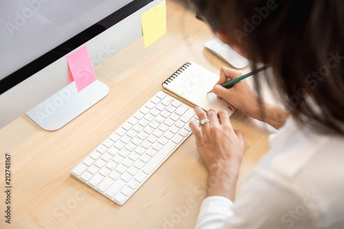 Woman writing note on paper at the table in the office
