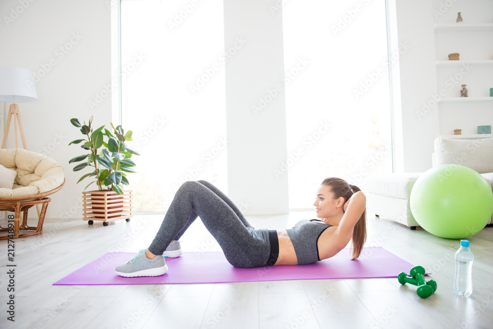 Profile side view photo portrait of charming gorgeous sporty sportive concentrated beautiful with ponytail brunette lady doing crunches on purple carpet at the weekend leading healthy lifestyle Profile side view photo portrait of charming gorgeous sporty sportive concentrated beautiful with ponytail brunette lady doing crunches on purple carpet at the weekend leading healthy lifestyle