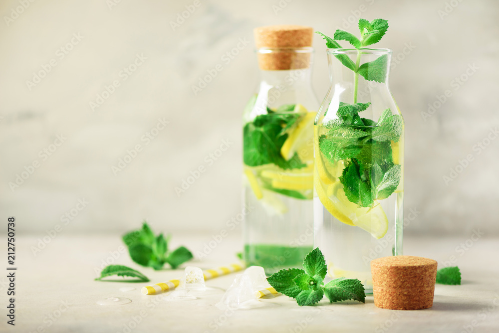Citrus lemonade - mint, lemon and tropical monstera leaves on grey background. Detox drink. Summer fruit infused water. Copy space.