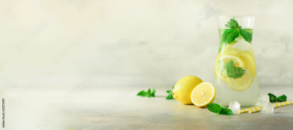 Detox water with mint, lemon on grey background. Banner with copy space. Citrus lemonade. Summer fruit infused water. Refreshing homemade cocktail, selective focus.
