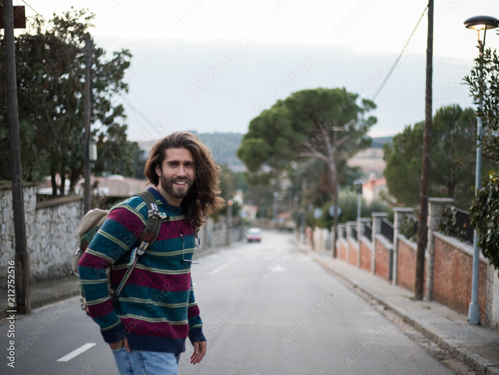 Man with long hair carrying a backpack Man with long hair carrying a backpack