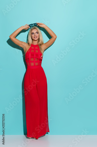 Beautiful Blond Woman In Red Dress Is Holding Sunglasses And Looking Away