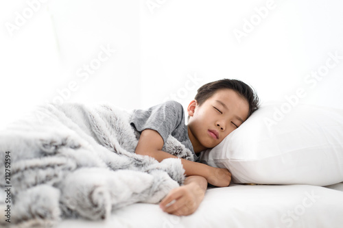 Boy sleeping alone on a white bed.