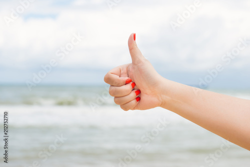 Woman's hand on a background of the sea show okay © makistock