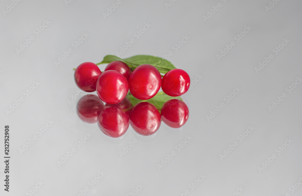 berries of ripe cherries and their reflection on a mirror surface, on an isolated background berries of ripe cherries and their reflection on a mirror surface, on an isolated background