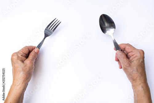 Senior woman's hands holding silver spoon and fork isolated on white background