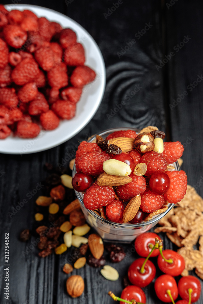 homemade yoghurt with flakes, nuts and berries of raspberries and cherries on dark wooden background homemade yoghurt with flakes, nuts and berries of raspberries and cherries on dark wooden background