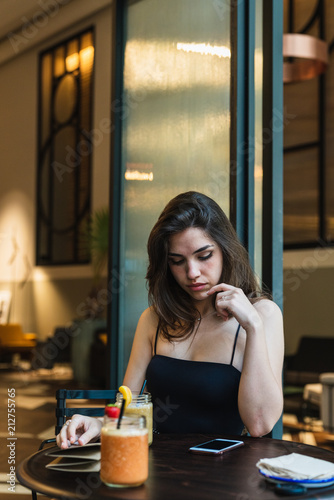 Woman at cafe table looking down