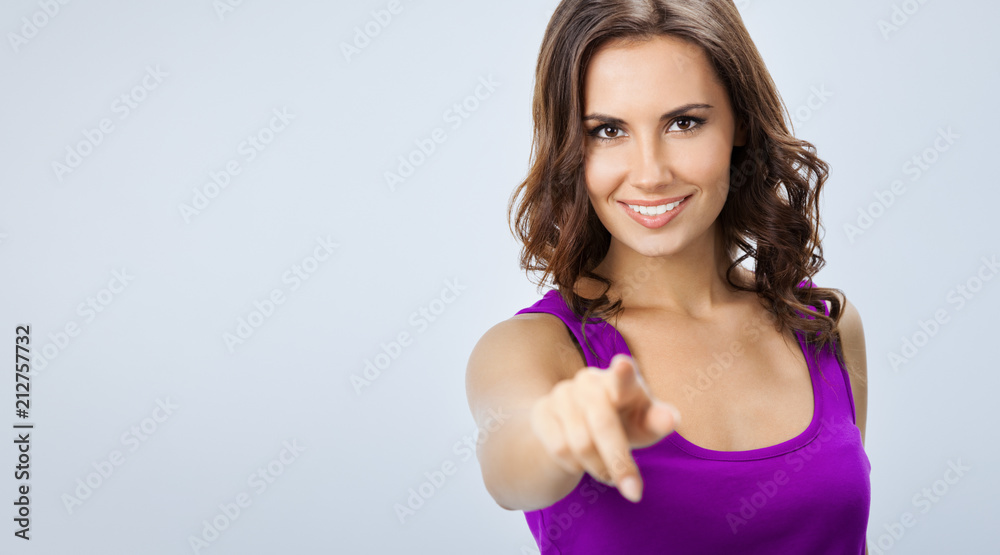 Woman pointing at something or pressing virual button, over grey Woman pointing at something or pressing virual button, over grey