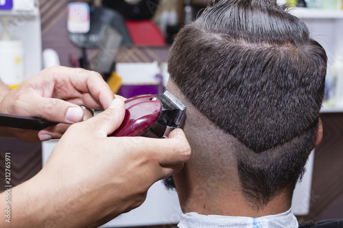men's hair Styling and grooming with the help of scissors machine and hair clippers in the hair salon.
