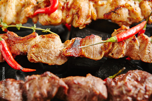 Hot Grilled Pork Kebab or Barbecue Shashlik on Charcoal Background with Herbs and Spices Closup photo