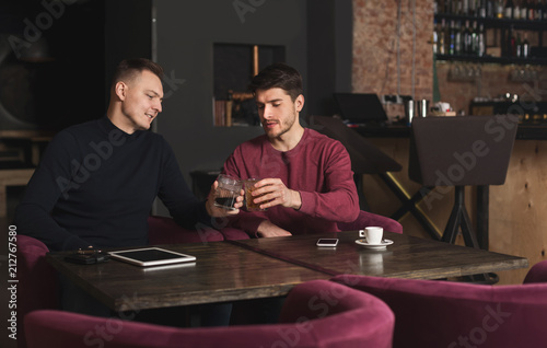 Two happy young men talking and drinking whiskey photo