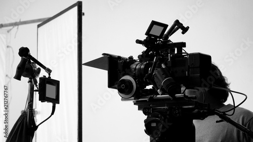 Movie shooting or video filming production by crew team and professional equipment such as super ultra high definition digital camera with tripod and lighting set in studio and black and white styles.