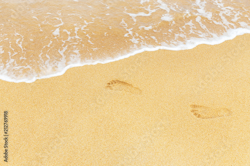 footprints in wet sand with white soft wave on the tropical beach