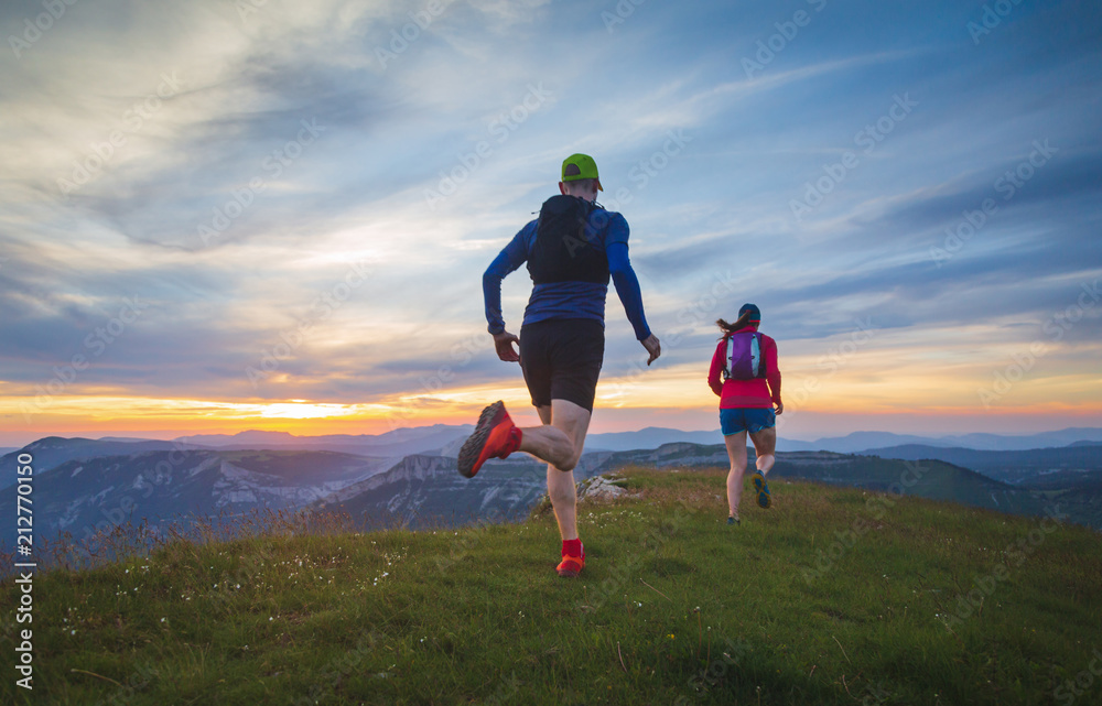 Two athletes trailrunning in the hills during sunset. Shallow D.O.F. Two athletes trailrunning in the hills during sunset. Shallow D.O.F.