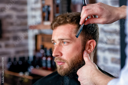 Hairdresser shaves man's beard with a blade
