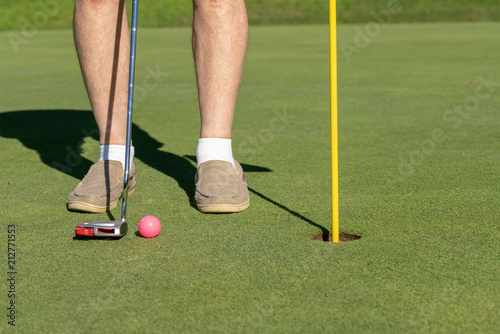 Pink golf ball by flag and hole on putting green photo