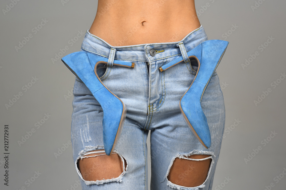 Sexy girl with a naked stomach in jeans and blue high-heeled shoes.  Fashionable clothes and shoes. Style and fashion. Denim background. Modern  woman, style icon. Blue concept. Designer of clothes Stock Photo