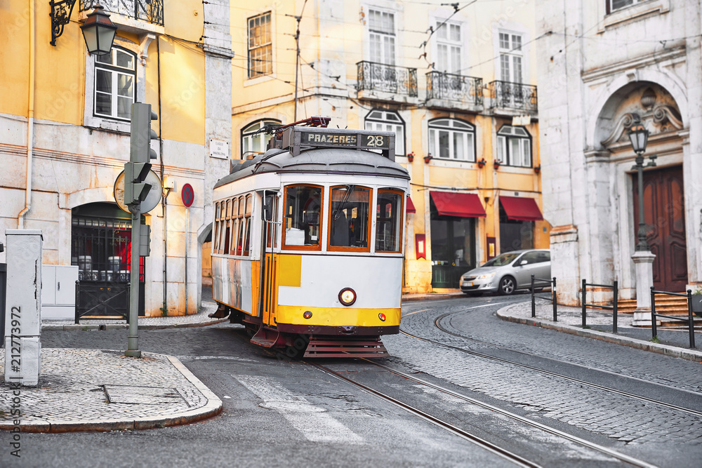 Fototapeta premium Lizbona, Portugalia. Vintage żółty tramwaj retro na wąskiej bocznej uliczce