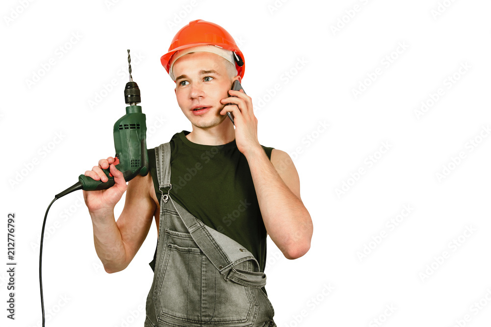 Young working guy in hard hat holds drill and speaks by phone isolated on a white background Young working guy in hard hat holds drill and speaks by phone isolated on a white background