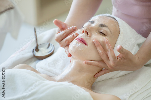 Young beautiful girl in mask for face relaxing in spa salon .woman treatment  massage with facial mask on face photo