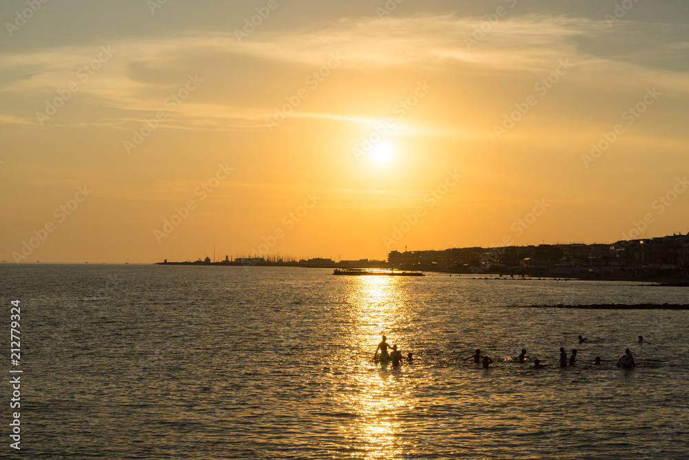 Children playing in the sea and enjoying sunset in Ostia Lido, Roma, Italy