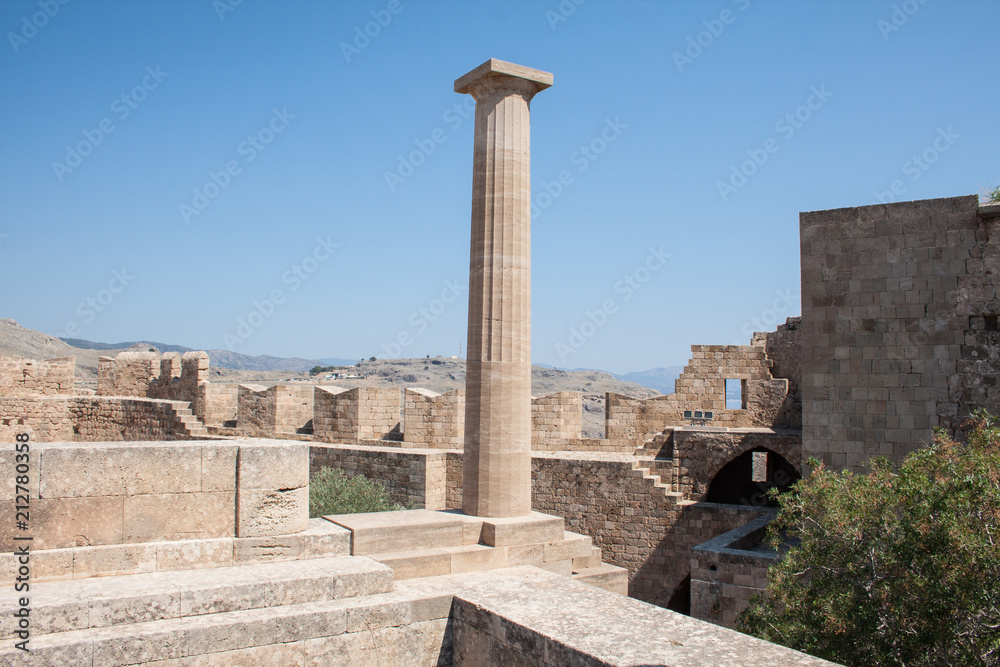 Columns on the hellenistic stoa of the Acropolis of Lindos, Rhodes, Greece, Blue sky, olive tree and beatiful sea view in the background