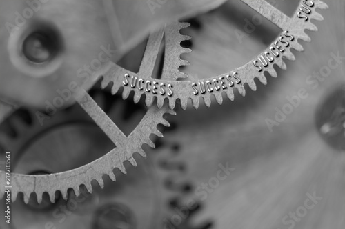 Background with the inscription Success. Black white background with metal cogwheels clockwork. Macro. Conceptual photo for your successful business design. Metallic black and white letters, gears.  