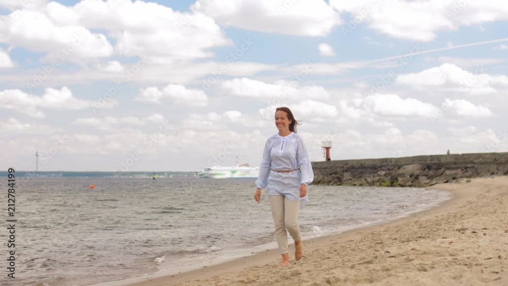people and leisure concept - happy smiling woman walking along summer beach people and leisure concept - happy smiling woman walking along summer beach