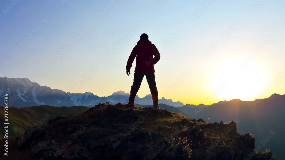silhouette of man standing on the mountain face to sunrise.