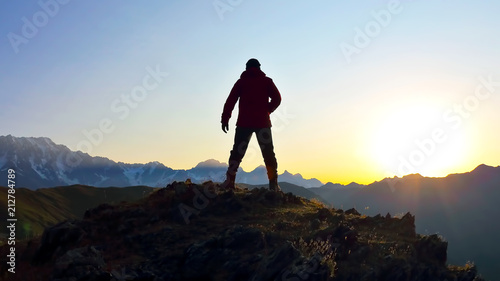 silhouette of man standing on the mountain face to sunrise. © photosaint