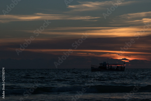 Silhouette of boat on the horizon at sunset on the beach