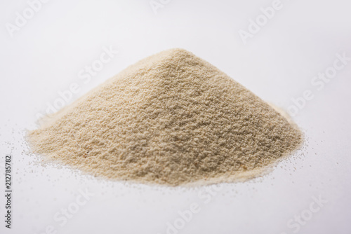 Raw unprepared semolina flour also known as Rava powder over white or moody background. selective focus