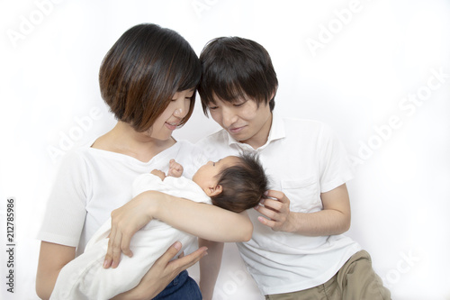 新生児を抱き見つめる若い夫婦、幸せな家族イメージ