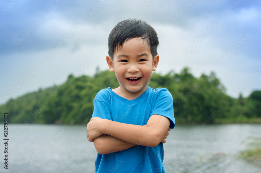 Portrait of a beautiful asian boy in the park, standing with arms crossed and smiling with copy space image. Portrait of a beautiful asian boy in the park, standing with arms crossed and smiling with copy space image.