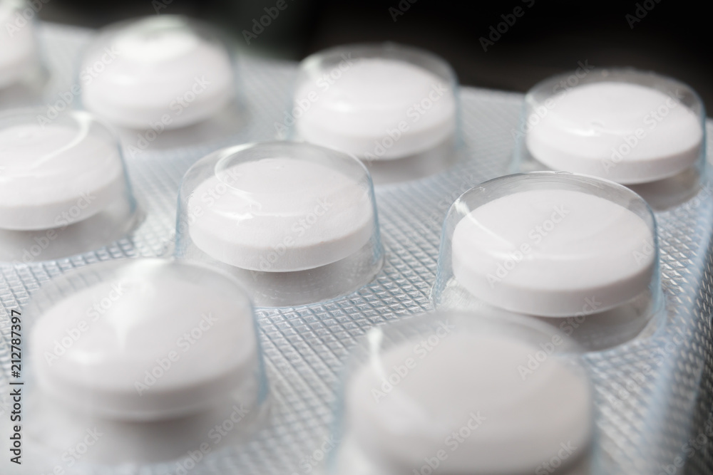 Round tablets on a black background in the package Round tablets on a black background in the package