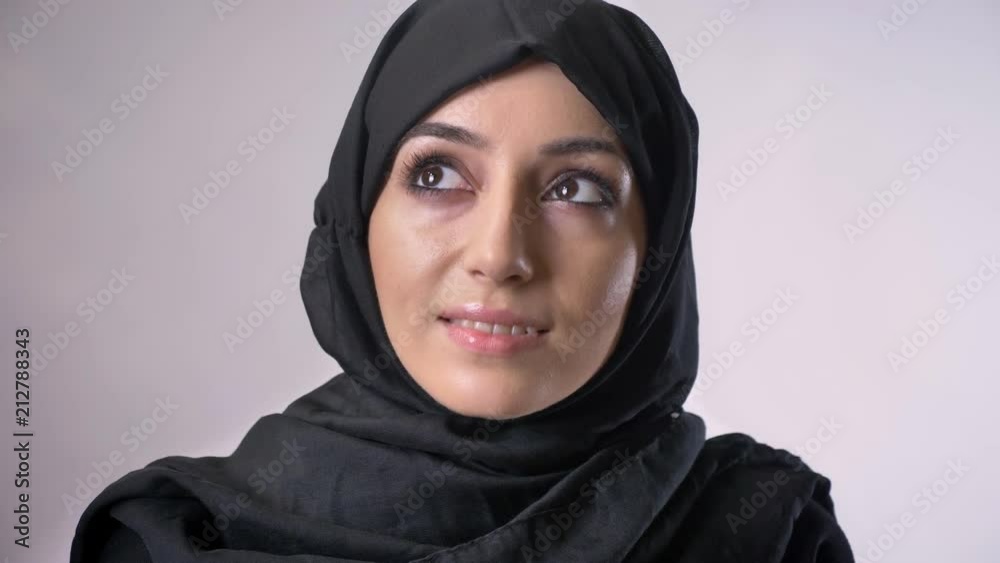 Young sweet muslim girl in hijab is watching at camera, dreaming concept, religious concept, grey background