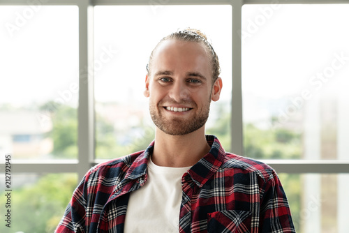 Portrait of young happy short stylish bearded caucasian man or creative designer smiling and looking at camera feeling confident in casual outfit. Headshot of male employee, entrepreneur or student.