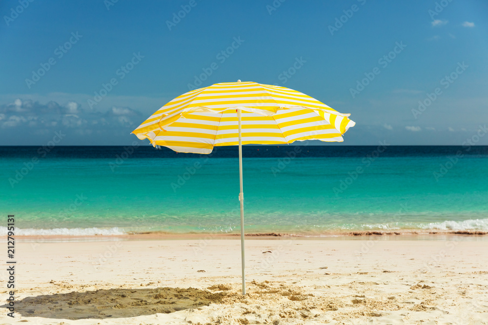 Yellow umbrella in the sun on pristine sandy Barbados beach