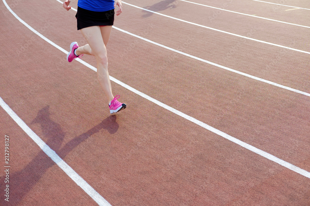 Athletic young woman in pink sneakers run on running track stadium