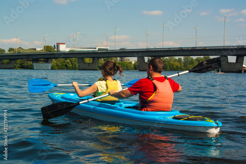 Young couple kayaking down the river in a blue kayak on a beautiful sunny day